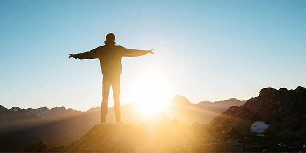 Man standing on with arms outstretched to sun